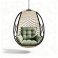 Hanging rattan chair with green cushion for indoor and outdoor use